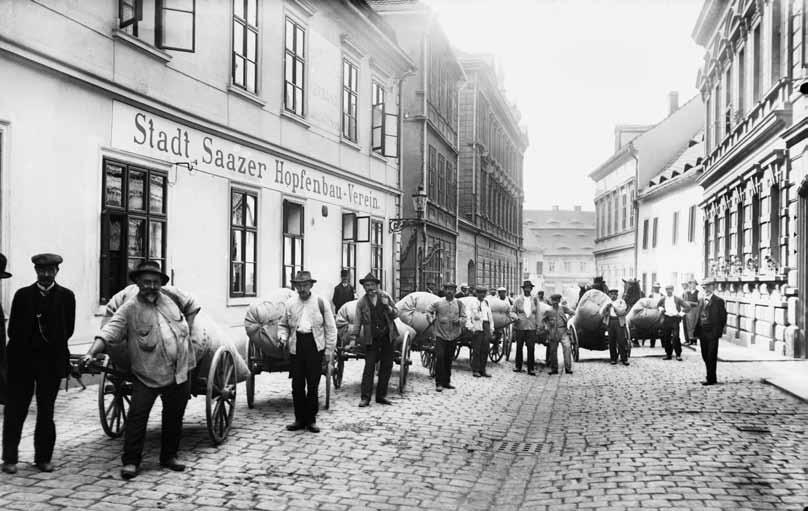 109 Služby navázané na chmelařskou produkci: kolečkáři, přepravující chmel na krátké vzdálenosti, čekají se svými vozíky před budovou známkovny žateckého Hopfenbau-Vereinu (před rokem 1918)