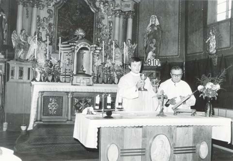 Prvomájový průvod prochází kolem fary a kostela, r. 1982 ústřední topení. P.