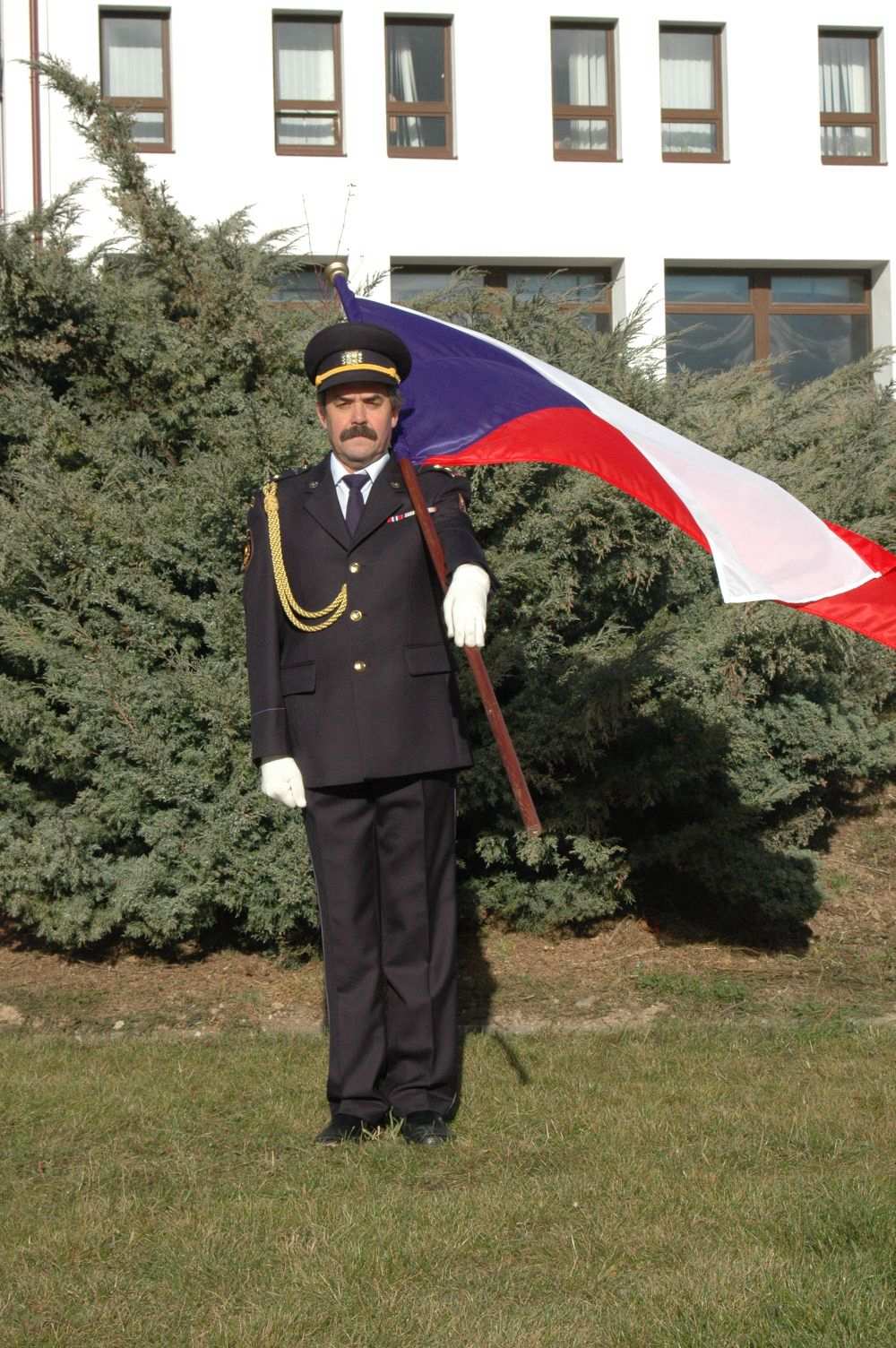 9) Vlajkou se vzdává pocta na místě tak, že praporečník uchopí žerď ze základního postoje levou rukou ve výši pravého ramene a rázně skloní prapor pod úhlem 45.