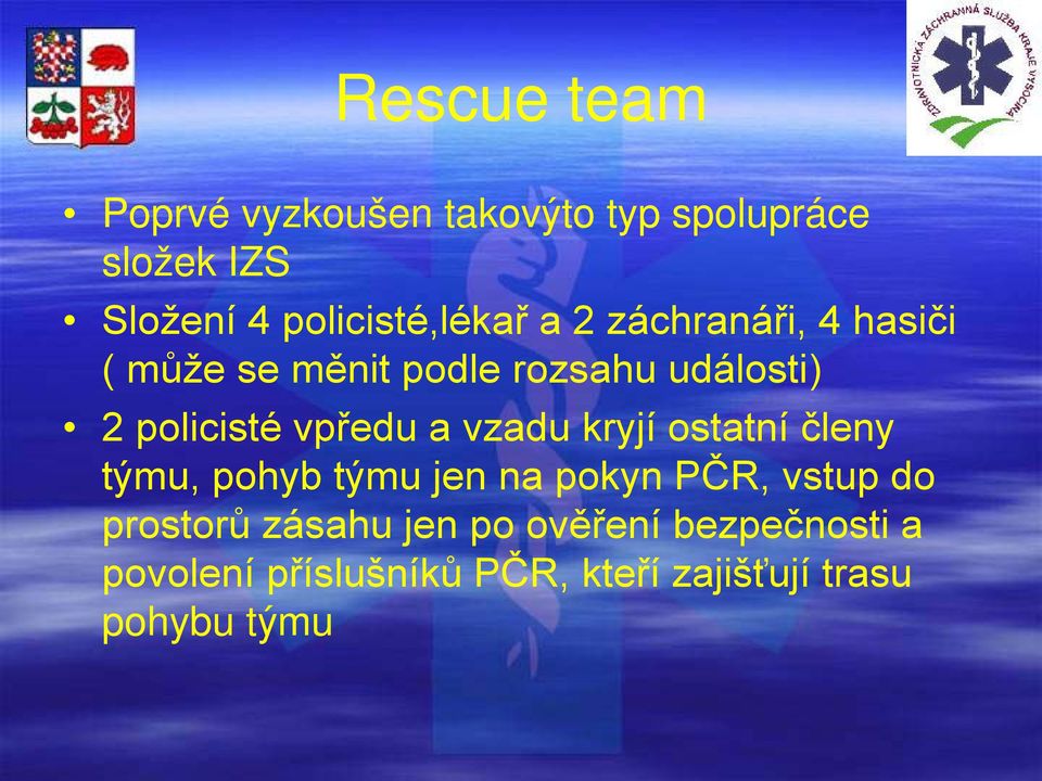 policisté vpředu a vzadu kryjí ostatní členy týmu, pohyb týmu jen na pokyn PČR, vstup