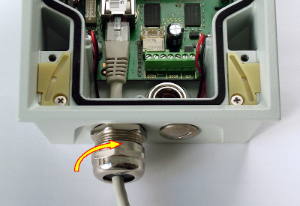 4. Na těsnění navlékněte pouzdro. 5. Koncovku kabelu protáhněte tělesem průchodky dovnitř interkomu a zacvakněte do konektoru na základní desce. 6.