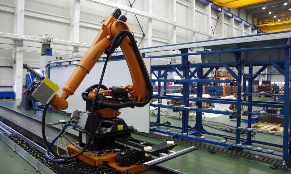 Obr. 5.9: Průmyslový robot firmy KUKA na lineárním pojezdu. V pozadí je patrný skladovací regálový zásobník [TOS Kuřim OS, a. s.].