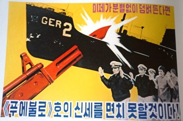 obr. 44 - Propagandistický plakát I když američtí imperialisti bezhlavě kopou kolem sebe, neuniknou osudu lodi Pueblo!