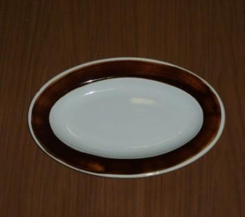 274. TALÍŘ Inv. č.: 10E 274 Popis: talíř oválného tvaru, glazura bílé barvy, okraj zdoben tmavě hnědým nátěrem.