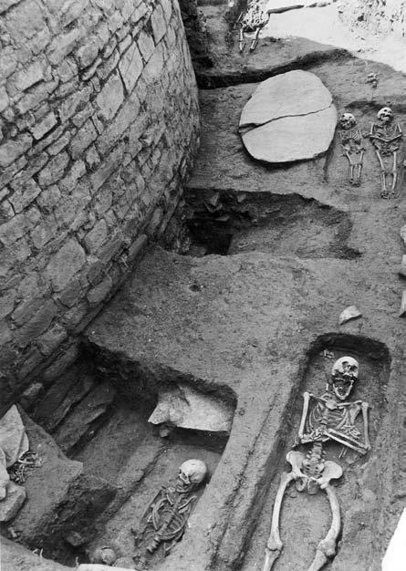 Obr. 34. Část hřbitova u rotundy v Pustiměři na Moravě. V pozadí je kamenná náhrobní deska. Foto: Archiv Archeologického ústavu AV ČR v Brně č. 20845/6.