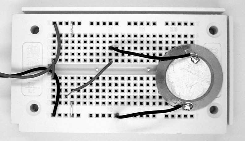 V praktickém experimentu (viz další schéma) můžete obvod vybavit flexibilním tlačítkem, vyrobeným z kusu vodiče. Při nabíjení měniče vždy uslyšíte malé zapraskání.