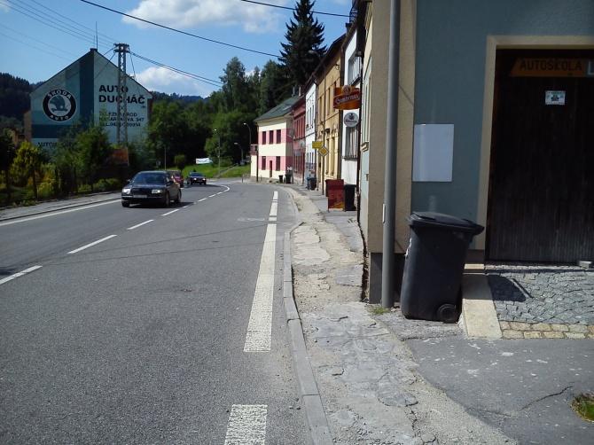 označník. Nerovný povrch. Pevné překážky ve vodící linii. Chodník částečně chybí.