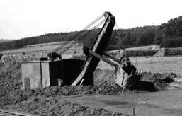 (Pojízdný pásový stavební jeřáb o nosnosti 2 tuny, fotografie 1), vedle stavebního stroje je ing. Karlsten (muž s hůlkou), jeden z vedoucích pracovníků firmy Hermann Milke.