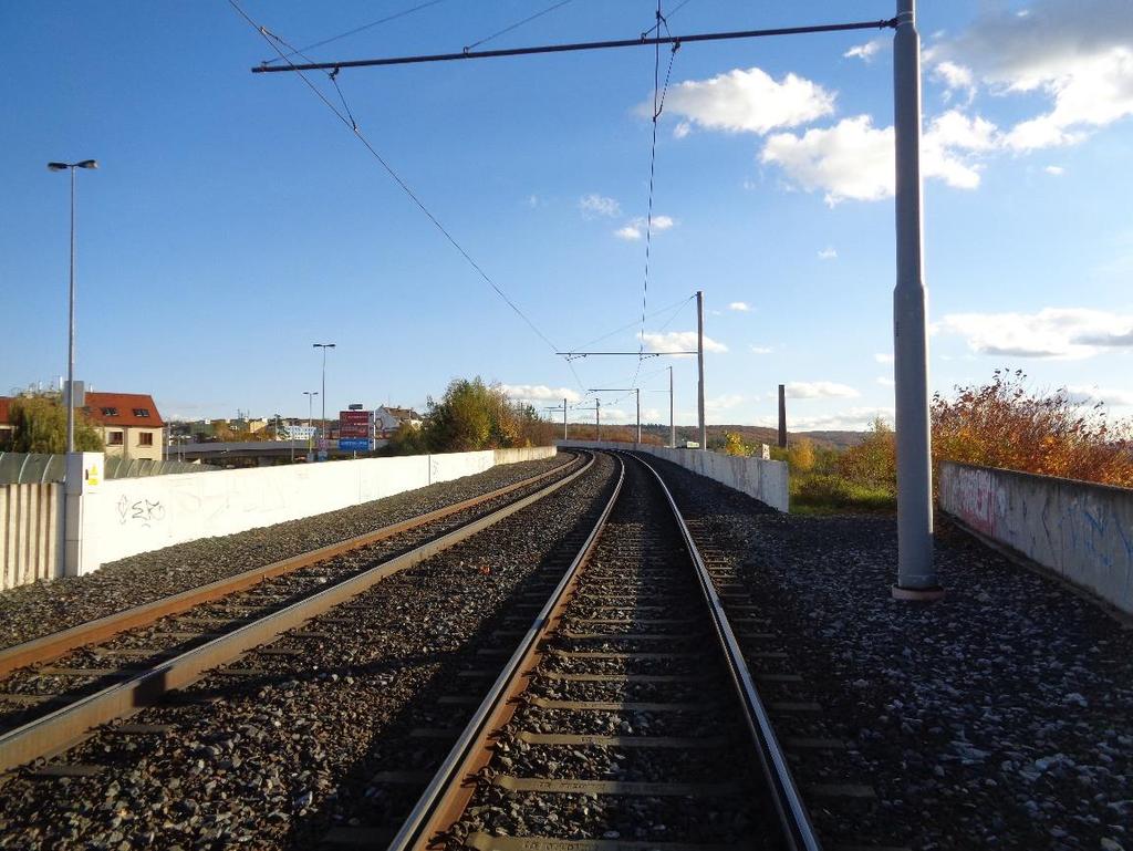 Obrázek 2 Pohled na ostrovní nástupiště výhybny Praha-Modřany zastávka. Vlevo zastávka tramvajové trati směr Sídliště Modřany. V pozadí komín umístěný ve zdemolovaném areálu modřanského cukrovaru.