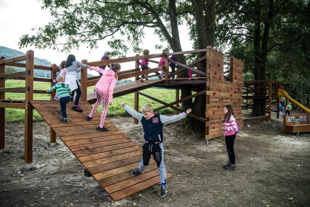 ve stromech, komunitní ohniště, pocitový chodník a lavičky kolem rybníku.