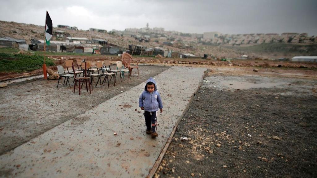 Palestinské dítě se běží schovat před deštěm ve škole na Západním břehu.