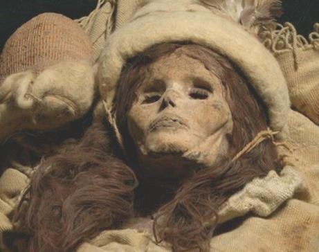Kráska z Xiaohe, další z tarimských mumií, s bílou vlněnou čepicí a plédem.