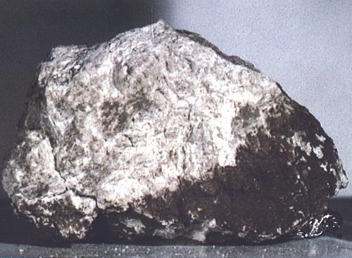 Obr. 2 Anortozit, převládající a nejstarší hornina měsíčních pevnin. Vzorek přivezený Apollem 15 z úpatí hory Mons Hadley pohoří Apenin; stáří kolem 4,4 miliard let, velikost asi 8 cm krát 5,5 cm.