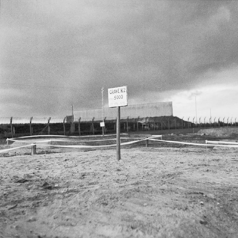 Oběti táborů smrti Fotografie zasypaného masového hrobu (koncentrační tábor Bergen-Belsen, Německo, 1945). Na nápisu u hrobu stojí: Hrob č. 2: pohřbeno 5 000 lidí.