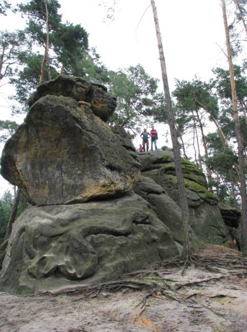 sedící vedle monumentálních reliéfních hlav.