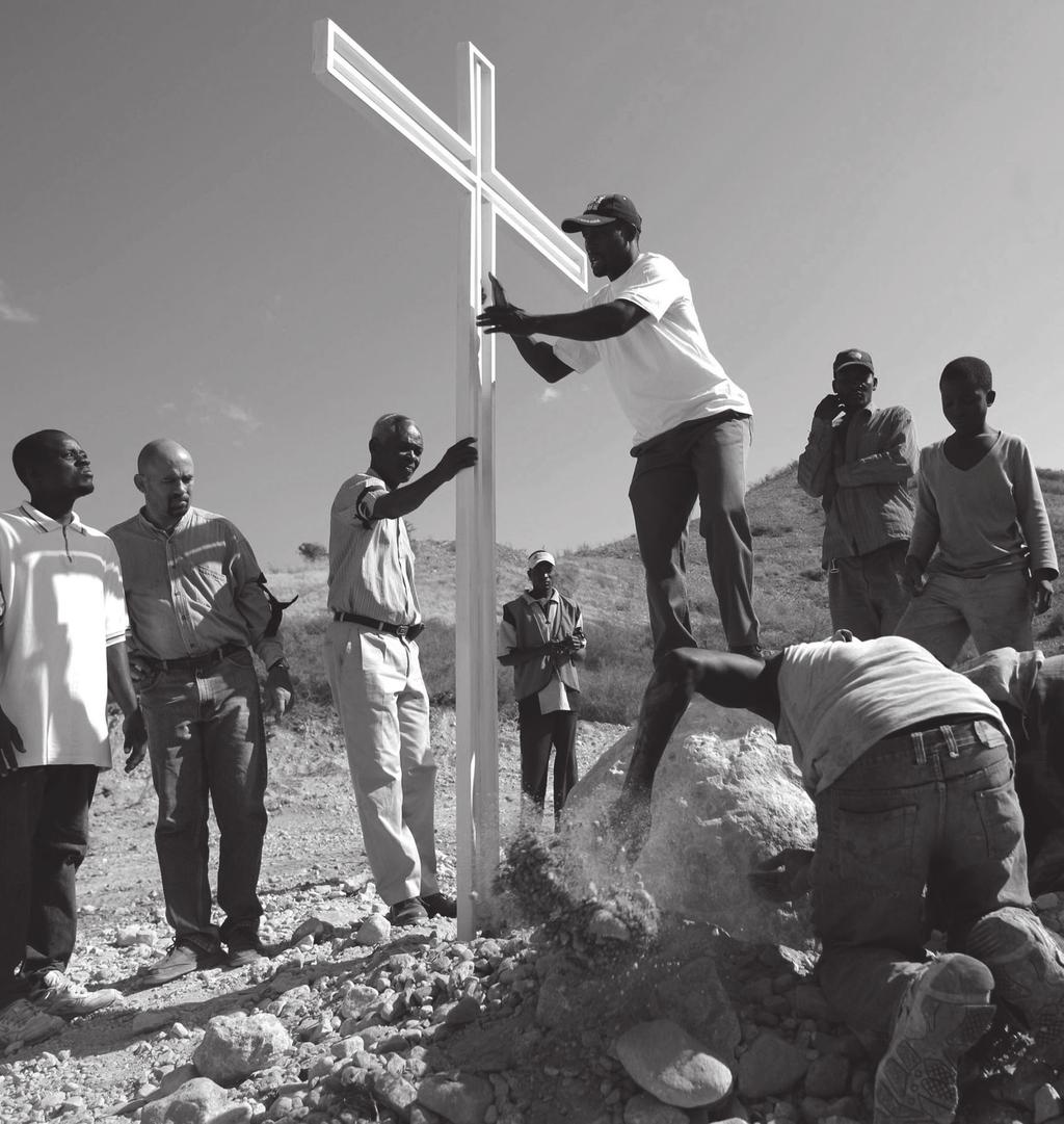 Ludźo postaja dnja 1. februara 2010 křiž na masowym rowje w Titany, 30 km před Port-au-Prince, Haiti 3.