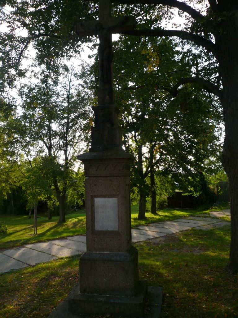 Text na kříži: Kříž z roku 1898, vlevo u silnice do Oslavan (u bývalých jatek) není památkově chráněn, neznámý autor.