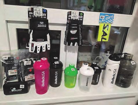 Na recepci sportovní haly jsou k prodeji připraveny sportovní doplňky fitness šejkry na protein, barely, lahve na pití, rukavice na cvičení, krabičky na sportovní výživu atd.