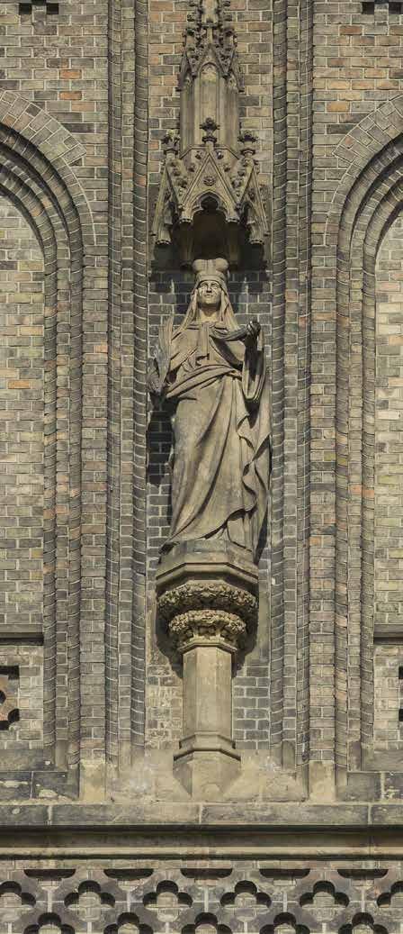 Socha sv. Ludmily na západním průčelí Nad hlavním portálem se nachází bohatě členěná rozeta, doplněná reliéfními medailony se symboly čtyř evangelistů od sochaře Jindřicha Čapka.
