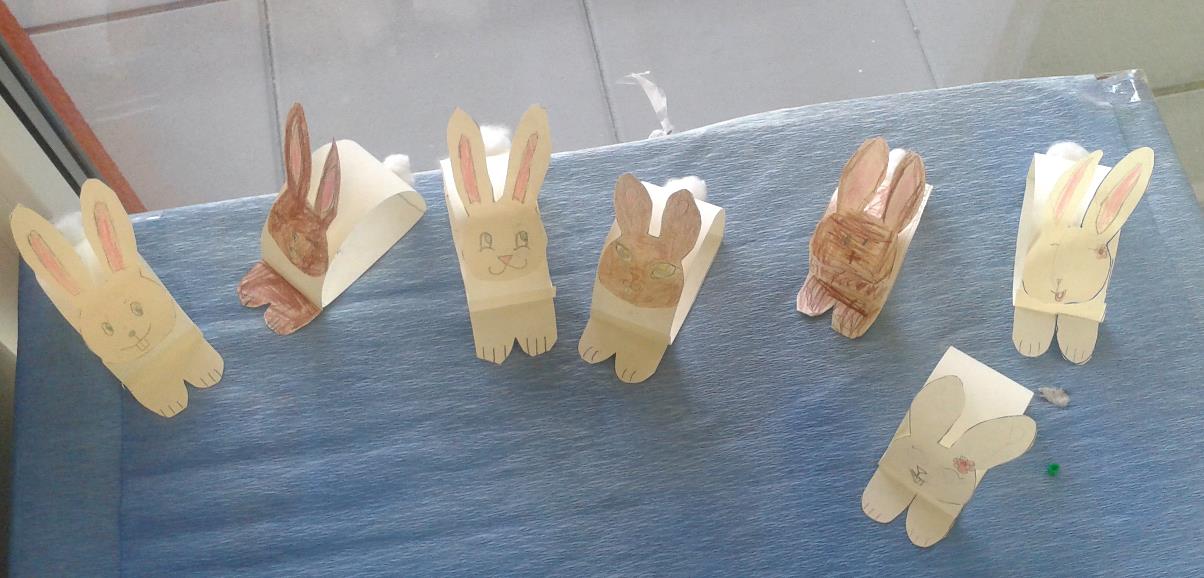Králíčci Pomůcky a materiál: barevný papír, tužka, nůžky, pastelky, vata, tubové lepidlo Postup práce: Z barevného papíru (nejlépe hnědý nebo krémový) vystřihneme obdélník široký 4 cm a dlouhý 18 až