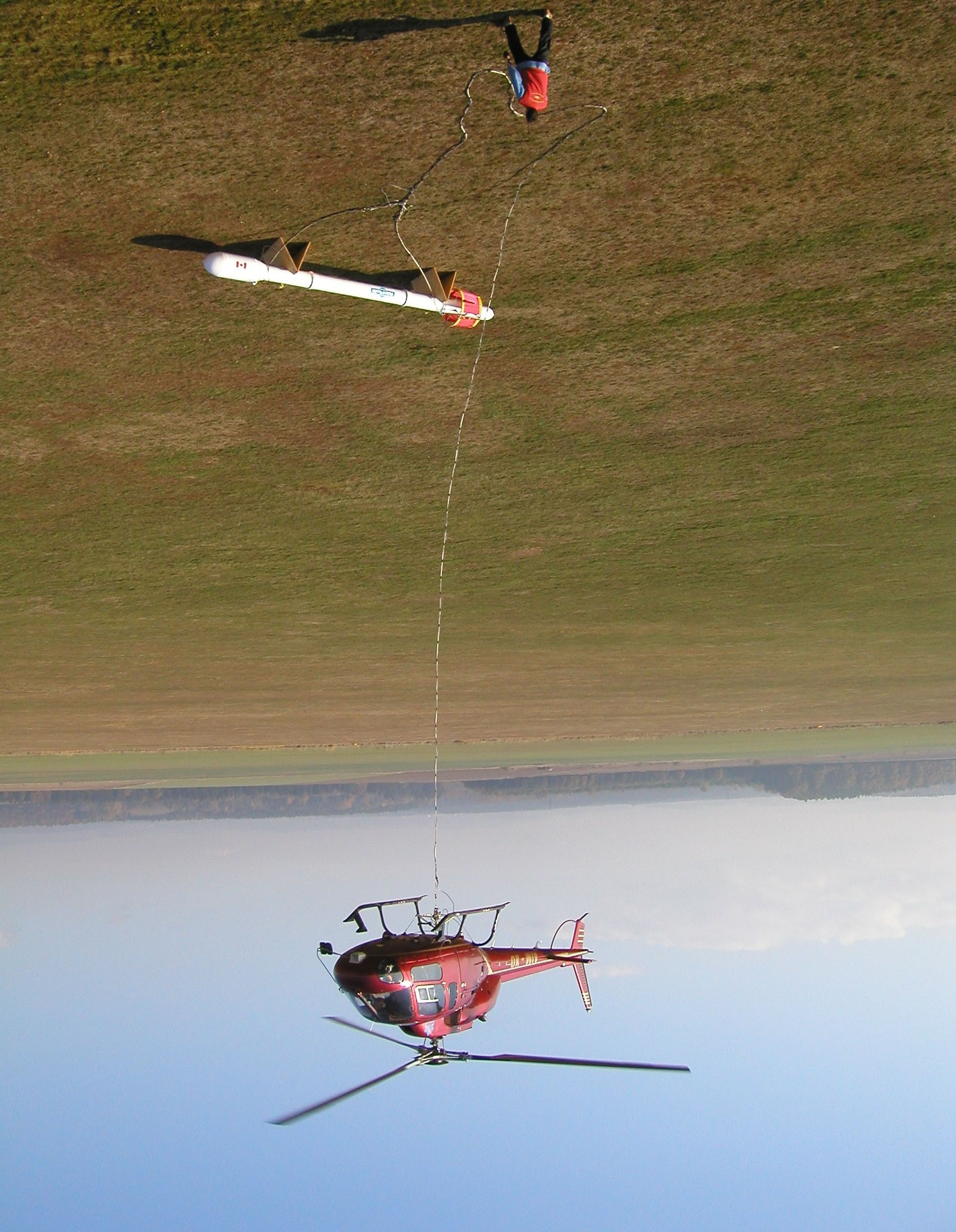 Obr. 2: Helikoptéra s elektromagnetickým snímačem HUMMINGBIRD na 30 m laně Použitá metodika a postup prací K provedení leteckých geofyzikálních měření byl zajištěn helikoptérový systém založený na