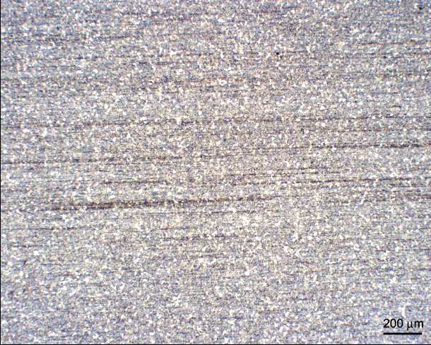 Obrázek 70. Vzorek C_1 zvětšen 50x Při 50násobném zvětšení lze pozorovat výraznou tvářecí texturu v podobě příčných čar, která vzniká při tažení materiálu průvlaky při výrobě.