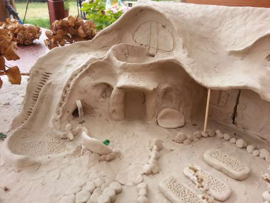 Model dostavby mateřské školky vyrobený z plastelíny. Tvárná hmota umožňuje umělecké propracování detailů zahrady. Podle modelu následně vzniká projekt a realizace.