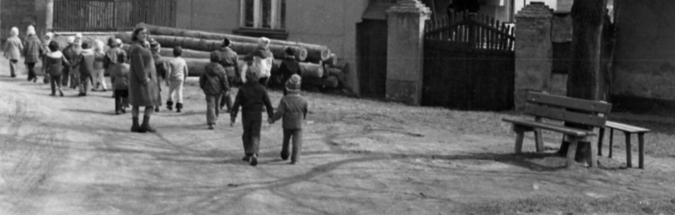 Ulice K Rybníku 39 Kolem domu čp. 21 procházejí v roce 1977, před přestavbou, děti z mateřské školy vedené Evou Saifrtovou. Snímek z fotokroniky Mateřské školy Hostivice.