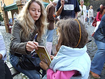 Obrázek nás zve na festival Jičín město pohádky, na kterém právě Ilona Pluhařová podepisuje jedné z malých čtenářek svoji stulíkovskou knihu. Foto: Žantovský (rok 2009).