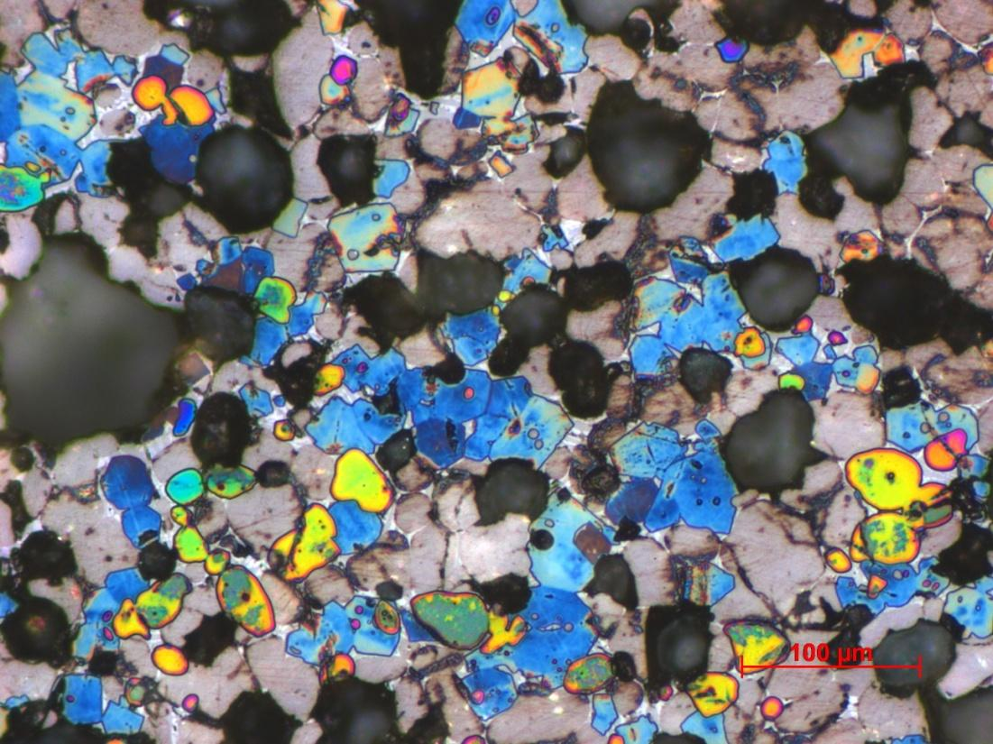 Obr. 22 Slínek 3C, modré krystaly alit, hnědošedá zrna belit, přebarvené oblasti (žlutá, oranžová, růžová, zelená) volné vápno, světlé