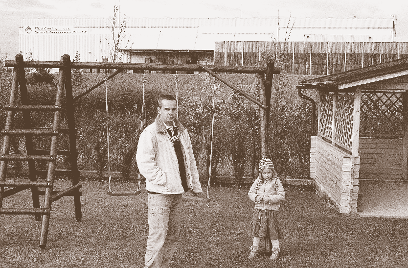 Ondřej Zapletal stojí se svojí dcerkou na zahradě domu, který si postavil v klidné lokalitě Úval u Prahy, aby unikl hluku velkoměsta.