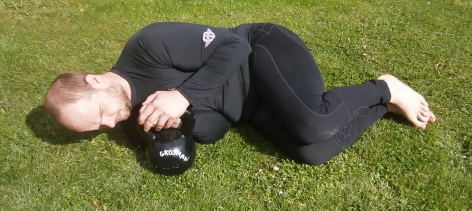 Poté se cvičenec otočí na záda a při tom zvedne kettlebell vzhůru do napnuté paže. Pravá dolní končetina je pokrčená a levá natažená v protažení těla viz obr. 5.