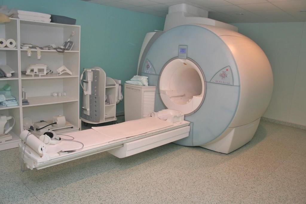 Samotný MRI přístroj je vzhledově velice podobný CT přístroji, viz. obrázek 16. Skládá se rovněž z posuvného stolu a gantry. Jak již bylo zmíněno víše, princip je ovšem zcela odlišný.