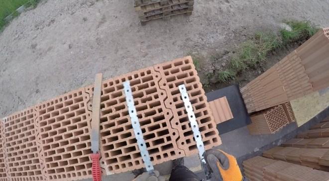 Založení stavby Cihlu jsem v místě uložení kotvy lehce zbrousil flexou nebo pilníkem, pásek namočil do lepidla případně podlepil pěnou a položil na cihlu tak, aby jeho polovina byla zazděna v