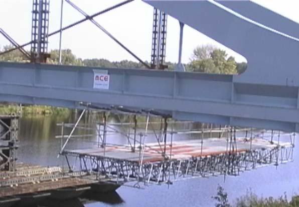 Obr. 0 Konstrukce zavěšené pojízdné lávky pro montáž bednění mostovky a nátěry, je vidět trojice vzájemně sešroubovaných a v dolním pase lanem sepnutých příhradových vazníků.