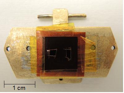 Obr. 5.7: Fotografie substrátu přikrytého kaptonovou maskou připevněného na paletce pro deponování v aparatuře IBAD (Kaufman) na ÚFI. Vytvoření této paletky s pěti kontakty, viz obr. (5.