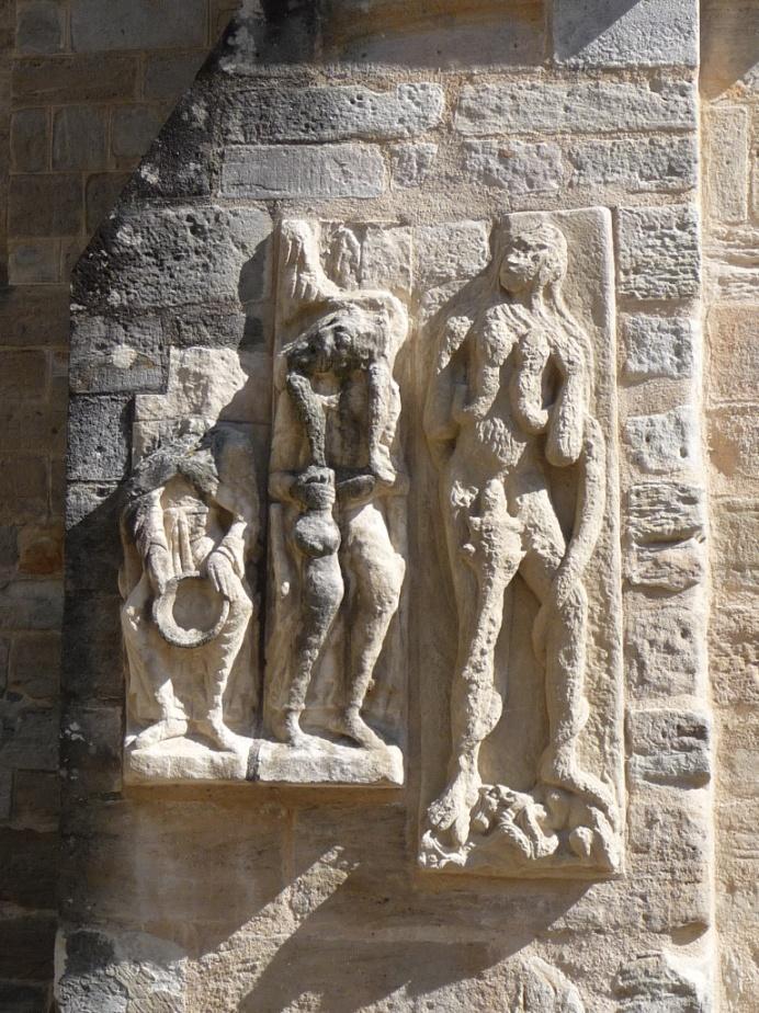 Obě vnitřní nároží portiku tvoří dva velmi poškozené reliéfy nesoucí monumentální ústřední postavy.
