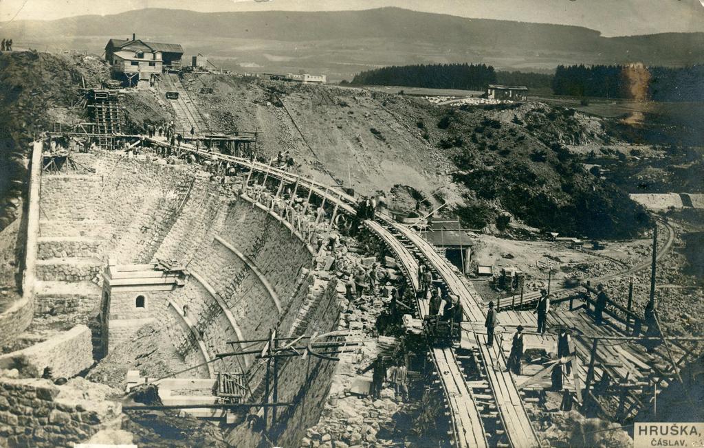 dopravována kolejovou drážkou. Délka hráze je 142 m, výška nad základem 31 m a nad terénem 24 m. V koruně je 4,5 m široká a v základech 23 m s celkovým objemem zdiva 35.000 m3.