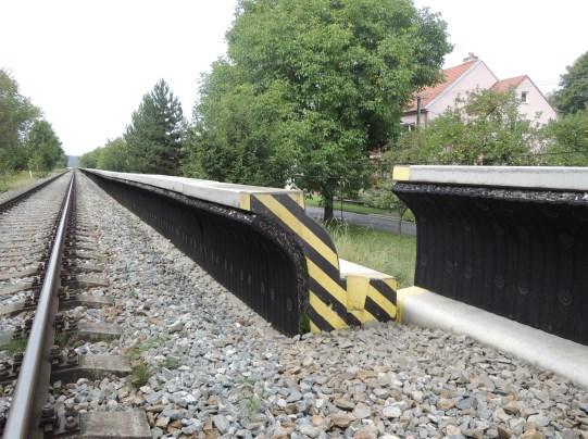 Příkladem takového opatření je nízká protihluková stěna Brens Barrier [10], vystavěná v roce 2013 na zkušebních úsecích v Praze Hlubočepích (obr. 4a) a v Tetčicích u Brna (obr. 4b).