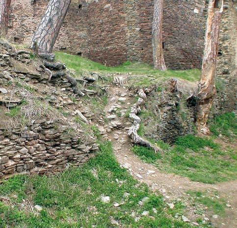 Ve spodní úrovni zdi je vidět doplnění líce, v horní úrovni (vlevo) zpevnění jádra zdiva bez lícové plochy. Koruna zdiva překryta drnovým pokryvem.