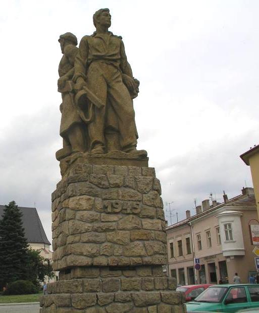 spojenými maltou, trojsoší symbolizuje různé kategorie pracujících, v předu stojí muž v rozhalené košili, držící v ruce samopal, o jeho levé straně žena, držící snop obilí, po pravé straně dělník s