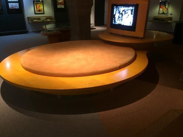 23. Velký kulatý světlý dřevěný stůl, dřevěný rám na 2 televize a