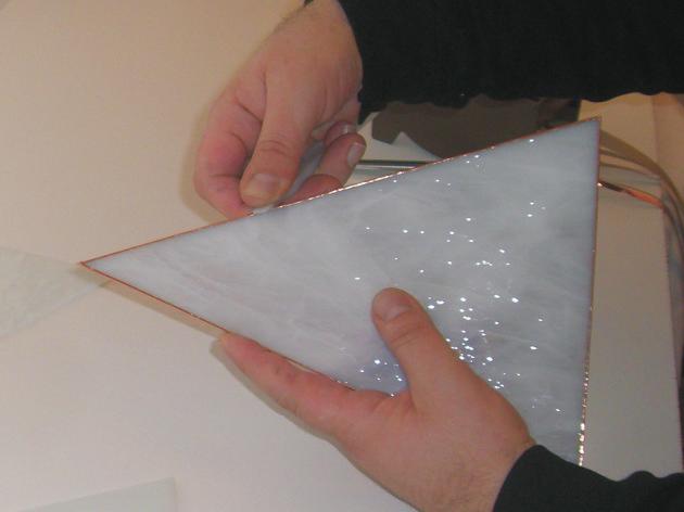 vložte fólii s ukazováčkem soustředěným kolem skla a lehce stiskněte fólie na strany. Ujistěte se, že sklo drží ve prostřed fólie.