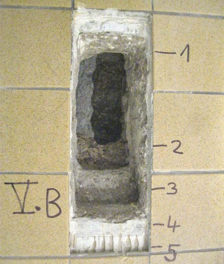 Sonda V. B v podlaze 1 hrubý beton s křemennými valouny jako plnivem. Uvnitř vložené dřevo a vlevo je kovová trubka.