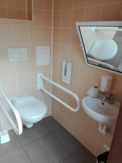 Dveře WC kabiny (průjezdová šířka 90 cm) jsou otevíratelné směrem ven a jsou opatřeny vnitřním madlem (výška 90 cm).