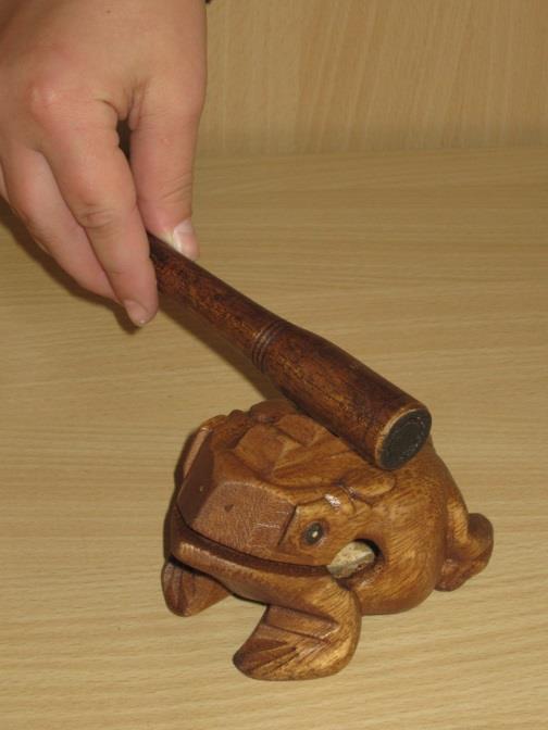 Dřevěná žába vydává zvuk jako skutečná žába. Zuby brzdí pohyb paličky a ba se rozkmitá.