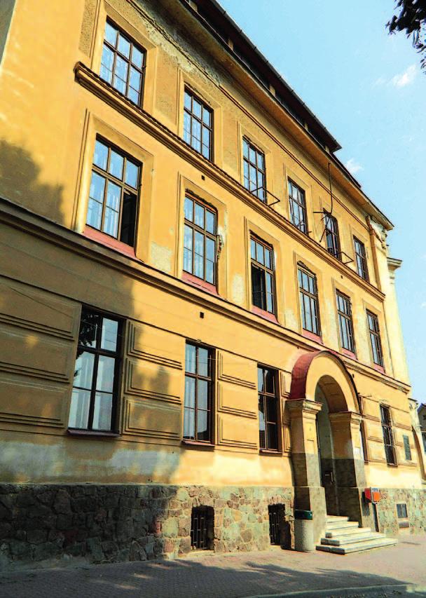 Z oken zní hudba i hlasitý smích, před budovou posedávají gymnazisté s plátny a po ulicích Komína občas poskakují malí kejklíři.