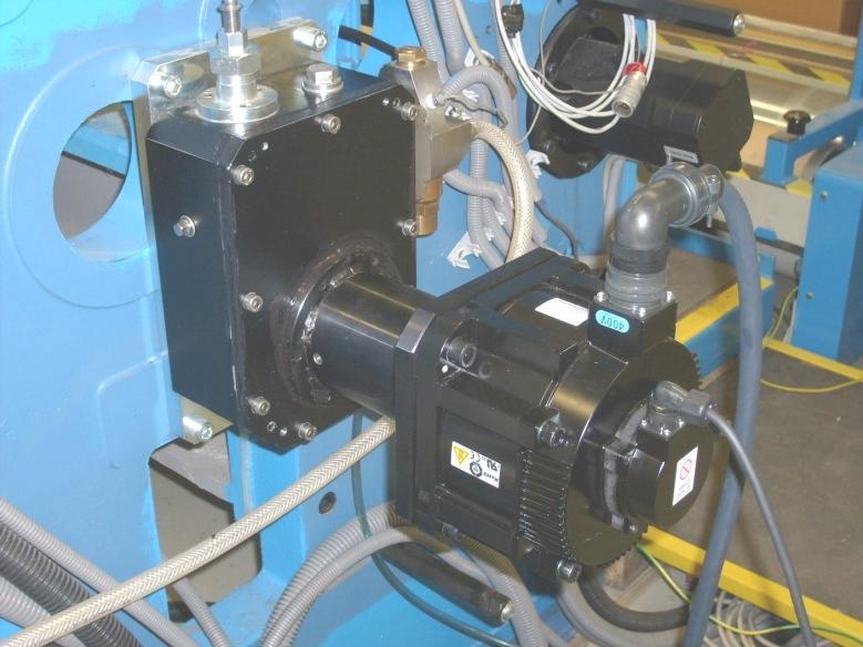 Zde elektronická vačka svojí pohybovou funkcí hřídele servomotoru pohání prostřednictvím řemenového převodu kliku čtyřkloubového a klikového mechanismu (na obrázku tyto