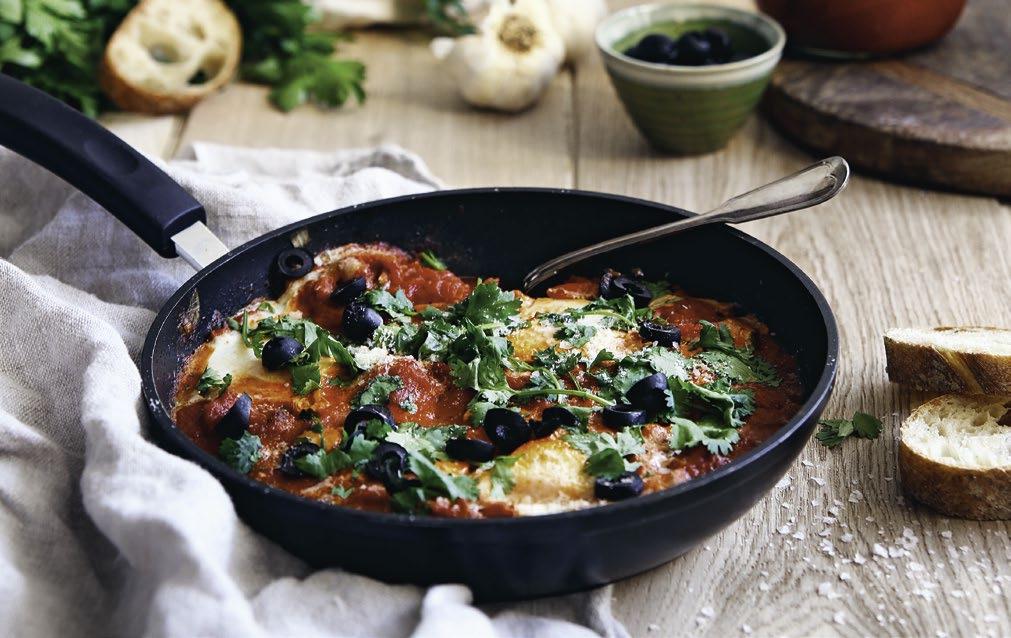 BRATISLAVSKÝ Shakshuka 3 PL olivového oleja 1 cibuľa 1 červená paprika 1 malá chilli 3 strúčiky cesnaku 2 ČL mletej rasce 800 g lúpaných paradajok soľ a čierne korenie hrsť koriandru 6 vajíčok olivy,