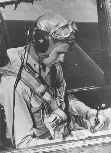 G. H. W. Bush (starší) si dělá levou rukou letové poznámky v kabině TBM Avenger v době 2.